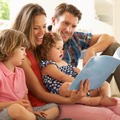 Parents Sitting With Children Reading Story Indoors