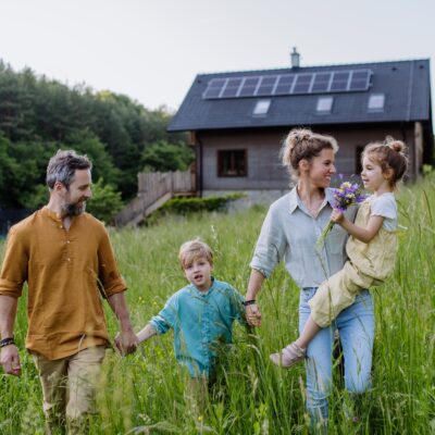 Happy,Family,In,Front,Of,Their,House,With,Solar,Panels