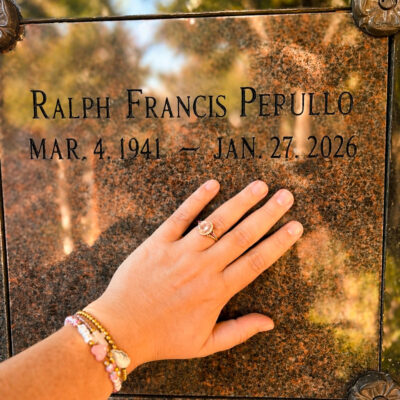 Hand gently touching engraved name on memorial plaque.