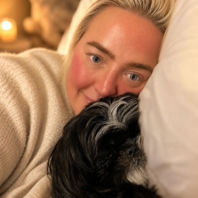 Woman resting with her dog while reflecting on grief, caregiving, health challenges, and the importance of self-care.